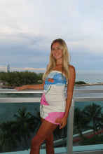 Load image into Gallery viewer, Woman in a colorful swimsuit standing by a pool with palm trees in the background
