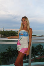 Load image into Gallery viewer, Woman in a colorful dress standing by a pool with palm trees in the background
