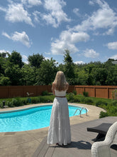Load image into Gallery viewer, Person standing by a pool with a clear blue sky and trees in the background
